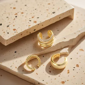 Three-piece set of twisted gold-plated ear cuffs with zircon inlay on stone surface