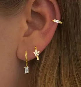Gros plan sur un ensemble de boucles d'oreilles en laiton doré avec zircons et étoiles