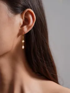 Primer plano de pendientes elegantes de doble perla con gancho dorado y forma de gota