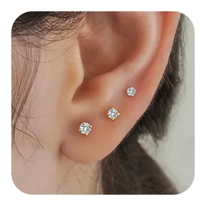 Three sizes of gold-plated brass stud earrings with clear zircon on model's ear