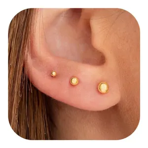 Detail view of a three-piece set of polished gold spherical stud earrings in various sizes