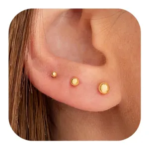 Three-piece set of polished golden ball stud earrings in varying sizes on model ear