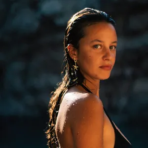 Gold starfish drop earrings worn by a model in a high-fashion summer beach setting