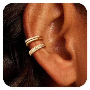 Dettaglio di un set di ear cuff dorati con zirconi incastonati sull'orecchio