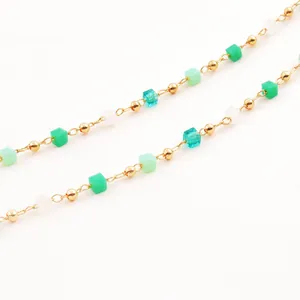 Détail de perles plaquées or et cubes de cristal verts sur un collier élégant