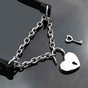 Close-up of heart-shaped padlock and key on black punk style cuban link chain
