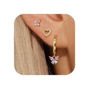 Close-up of gold butterfly and heart earrings set with sparkling pink zircon stones