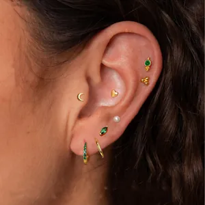 Chic gold brass star and moon earrings set with green zircon stones on model's ear