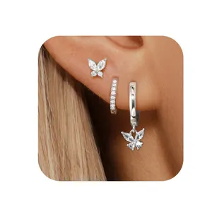 Macro shot of silver butterfly stud and zircon hoop earrings set worn on ear