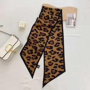 Close-up of leopard print satin neck scarf with black edges and washing label detail
