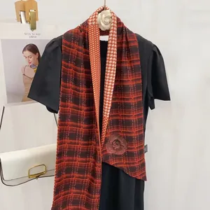 Détail d'une écharpe à chevrons rouge et orange portée sur une robe noire