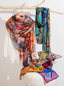 Detail of thin colorful printed silk scarves hanging on wood branch for daily styling