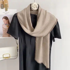 Detail of silk satin scarf with houndstooth pattern draped over a black dress