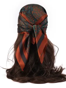 Close-up of silk-feel square scarf with burnt orange and green paisley floral patterns