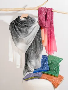 Dettaglio di scialli leggeri con stampa paisley colorata appesi a un ramo di legno
