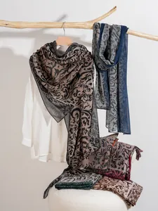 Detail of lightweight scarves with vine floral patterns hanging on a wooden branch