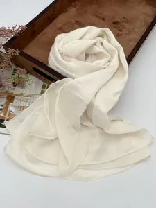 Dettaglio della sciarpa in chiffon plissettato bianco crema con texture fine e bordi orlati