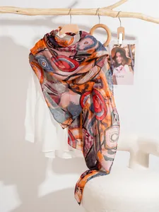Close-up of lightweight silk scarf with colorful abstract geometric patterns on a wooden hanger
