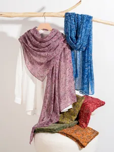 Detail of colorful floral pattern scarves on wooden branch showing texture and drape