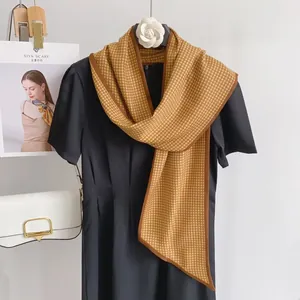 Detail of houndstooth silk scarf in brown and yellow draped on a black dress neck