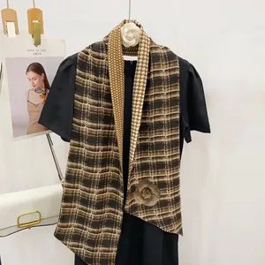 Détail de l'écharpe élégante à chevrons avec motif camélia et texture à carreaux