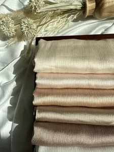 Macro di sciarpe in chiffon plissettato in colori neutri sfumati su vassoio di legno