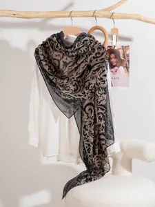 Detail view of vine print scarf in baroque style draped over wooden hanger