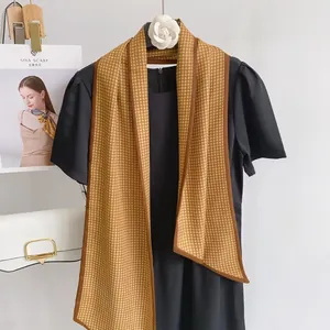 Elegant mustard yellow houndstooth silk scarf on a white camellia hanger display