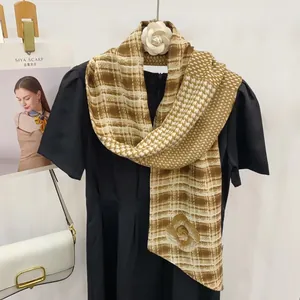 Détail de l'écharpe en soie à motif damier marron avec une broche fleur de camélia