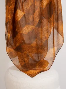 Dettaglio di un foulard in seta con stampa geometrica marrone drappeggiato su uno sgabello