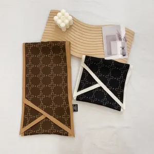 Detail of satin scarves featuring cross patterns with contrast borders and washing labels