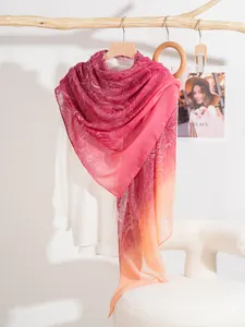 Dettaglio dello scialle paisley sottile con sfumatura rosso-arancio su un ramo