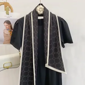 Detail of elegant black silk scarf with white geometric patterns and contrast border