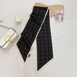Close-up of black silk twilly scarf with white floral patterns on a stylish white handbag