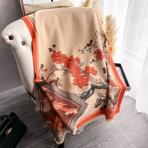 Dettaglio della sciarpa etnica floreale in finto cashmere con nappe e fiori arancioni