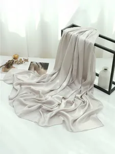 Dettaglio della trama di uno scialle in seta grigio chiaro su una cornice minimalista
