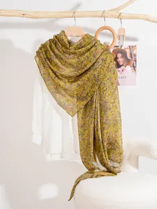 Detail view of lightweight floral silk shawl draped over a natural wooden hanger