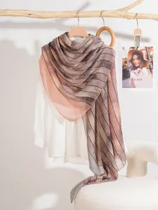 Dettaglio di sciarpa a righe sfumate drappeggiata con eleganza su camicia bianca e gruccia