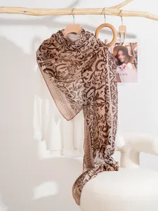 Detailed texture of lightweight vine print silk scarf with floral patterns on a hanger