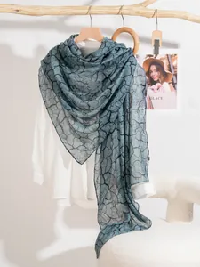 Dettaglio di sciarpa grigio-blu trama lino motivo pietra su gruccia di legno