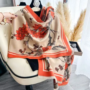 Dettaglio di sciarpa etnica in finto cashmere con fiori d'arancio e bordi con frange morbide