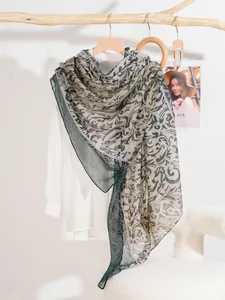 Close-up of lightweight vine print scarf in blue-grey styled on white shirt