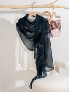 Dettaglio di sciarpa in seta a righe blu scuro drappeggiata su camicia bianca