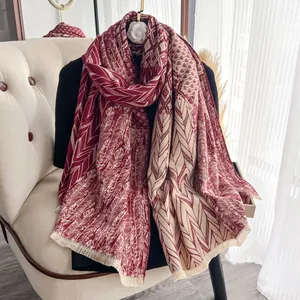 Dettaglio della trama geometrica e frange di una morbida sciarpa rossa effetto cashmere