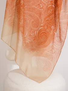 Dettaglio di una sciarpa leggera con stampa paisley in sfumatura arancio e beige