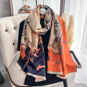 Dettaglio di sciarpa color-block con motivi floreali vintage e frange su poltrona