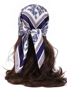 Detail of a floral paisley silk scarf tied on long wavy hair with a smooth glossy texture