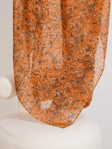 Detailed macro view of lightweight floral print scarf in elegant orange-brown tones