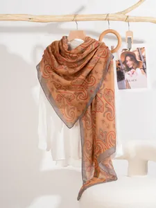 Dettaglio della sciarpa paisley zenzero su camicia bianca con bordo a contrasto