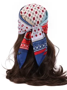 Detail of a vintage floral pattern silk-like headscarf tied on long brown hair